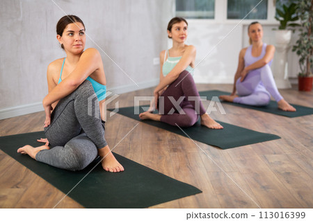 Young focused women doing sage pose in yoga studio Young focused women doing sage pose in yoga studio 113016399