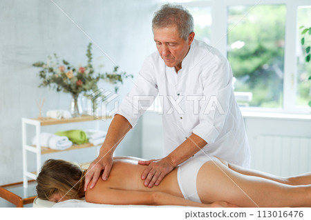 male masseur giving massage to female patient 113016476