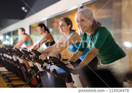 Mature woman taking cycling class at gym 113016478