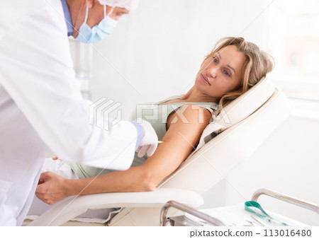 Man doctor makes an injection in arm of woman Man doctor makes an injection in arm of woman 113016480