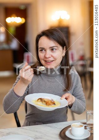 Cheerful woman enjoying apple strudel with espresso in coffee house Cheerful woman enjoying apple strudel with espresso in coffee house 113016485