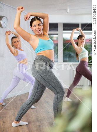 Girl practicing aerobics during group workout in fitness studio Girl practicing aerobics during group workout in fitness studio 113016492