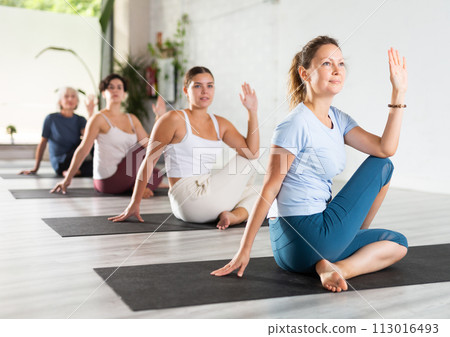 Portrait of women practicing Matsyendrasana known as Lord of Fishes Pose during group yoga training Portrait of women practicing Matsyendrasana known as Lord of Fishes Pose during group yoga training 113016493