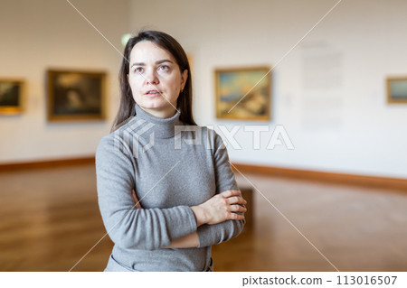 Brunette admiring artworks at paintings exposition in museum Brunette admiring artworks at paintings exposition in museum 113016507
