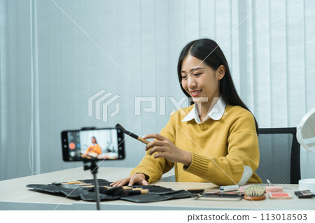 Asian teenage girls doing makeup vlogs and using a video mobile camera to record vlogs and publish them online at home. 113018503