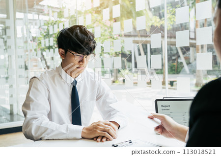 Male manager is talking or explaining about having to dismiss the employee while being handed out a resignation envelope to the employee. 113018521