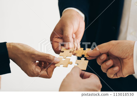The concept of teamwork and partnership. Businessman's hands putting together puzzle pieces in the office and join together in a jigsaw puzzle team. Charity. Volunteers. Business unity as a team. 113018530