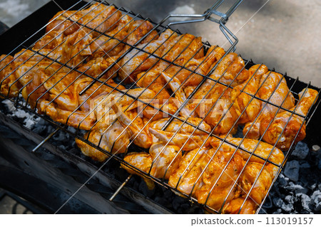BBQ picnic time Roasted chicken legs and wings on grill. Grilling meat on outdoor grill grid tasty barbeque chicken steak with smoke flames juicy meat in the backyard 113019157