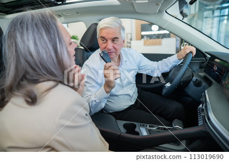 Mature Caucasian couple sitting in a new car and rejoicing at the purchase. Mature Caucasian couple sitting in a new car and rejoicing at the purchase. 113019690