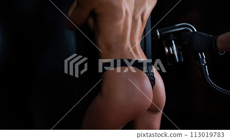 The master applies tinting paint on the back of a woman. Instant tanning treatment. The master applies tinting paint on the back of a woman. Instant tanning treatment. 113019783