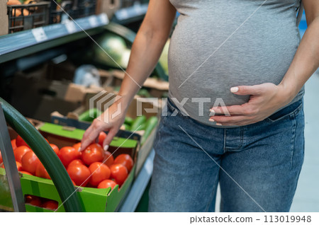 Pregnant woman buys tomatoes in the store. Pregnant woman buys tomatoes in the store. 113019948