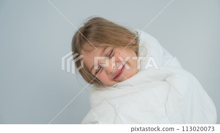 Portrait of a cute little girl wrapped in a white blanket.  113020073