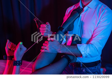 Sensual couple during role play. A man holds a woman by handcuffs. BDSM concept. 113020099