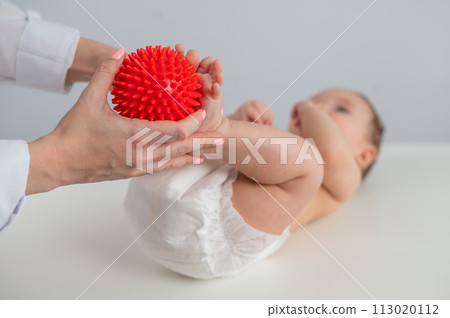A doctor massages a baby's foot using a spiked ball. 113020112