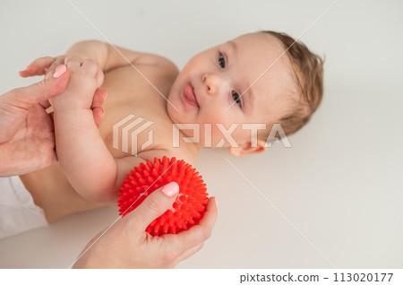A doctor gives a baby a shoulder massage using a ball. A doctor gives a baby a shoulder massage using a ball. 113020177