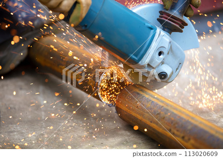 Worker's hands are cutting metal pipes with a grinder. Worker's hands are cutting metal pipes with a grinder. 113020609