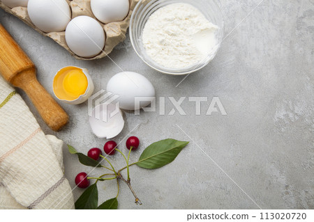 Ingredients baking flour eggs rolling pin berries kitchen textiles on gray background. Cookie pie or cake recipe mockup. Background preparation for culinary baking. Ingredients baking flour eggs rolling pin berries kitchen textiles on gray background. Cookie pie or cake recipe mockup. Background preparation for culinary baking. 113020720