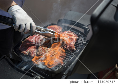 The chef's hands fry the meat.Grilled meat. Roasted piece of beef during cooking. The chef's hands fry the meat.Grilled meat. Roasted piece of beef during cooking. 113020747