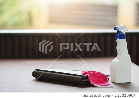 A bottle of cleanser and a medical mask on a restaurant table. 113020904