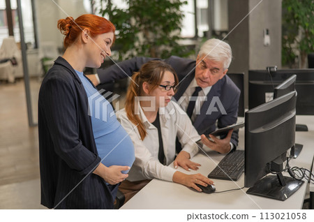 An elderly man, a Caucasian woman and a pregnant woman are discussing work issues at the computer. An elderly man, a Caucasian woman and a pregnant woman are discussing work issues at the computer. 113021058