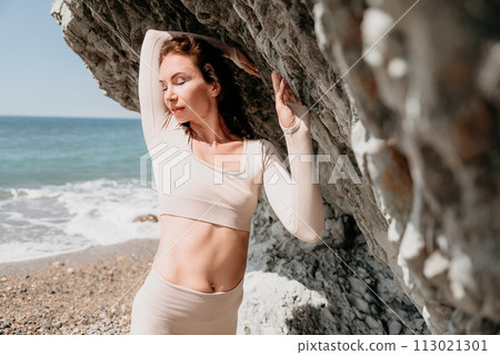 Woman travel sea. Sporty happy middle aged posing on a beach near the sea on background of volcanic rocks, like in Iceland, sharing travel adventure journey 113021301