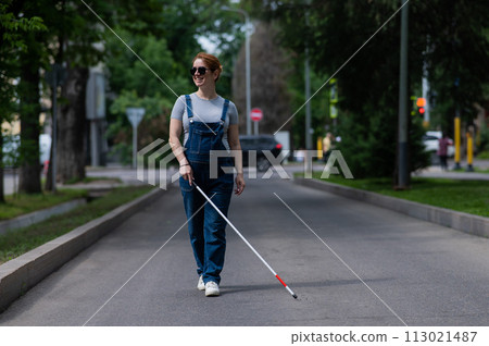 Blind pregnant woman walking down the street with a cane. Blind pregnant woman walking down the street with a cane. 113021487