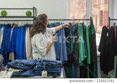 Caucasian fat woman chooses clothes. Plus size store.  113021581