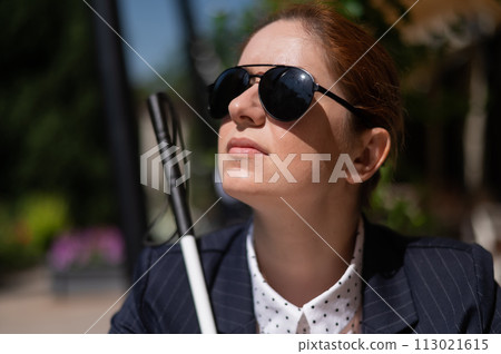 A blind woman in a business suit is sitting in an outdoor cafe. A blind woman in a business suit is sitting in an outdoor cafe. 113021615