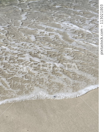 Waves crashing against a white sand beach 113021803