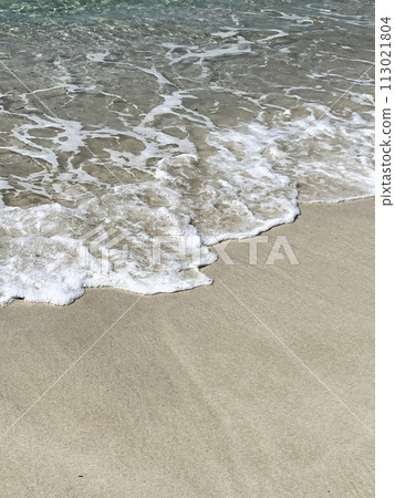 Waves crashing against a white sand beach 113021804