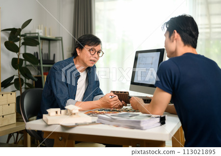 Professional interior designer discussing home renovation project with his client in office 113021895