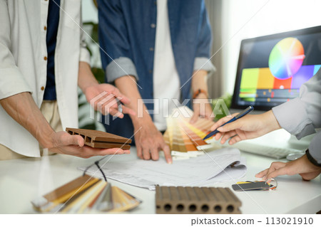 Group of designers of interior choosing material samples, working together at creative office 113021910