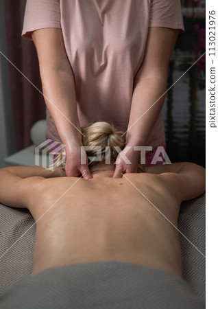 A woman undergoing a massage of the cervical-collar area. Vertical photo. A woman undergoing a massage of the cervical-collar area. Vertical photo. 113021976