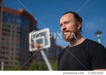 Portrait of a Caucasian bearded man on a basketball court outdoors.  Portrait of a Caucasian bearded man on a basketball court outdoors.  113022005