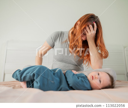 A woman sits on her child's bed and cries. Postpartum depression. A woman sits on her child's bed and cries. Postpartum depression. 113022056