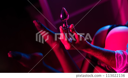 Man holding an anal plug. Close-up of female buttocks in underwear. Sexual preferences of the couple. Man holding an anal plug. Close-up of female buttocks in underwear. Sexual preferences of the couple. 113022136