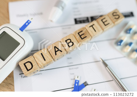 Lettering DIABETES on wooden cubes with pills, glucometer and blood sugar tests on table. 113023272