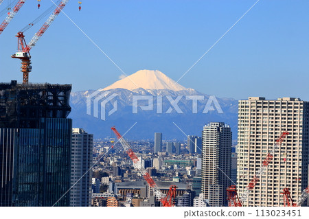 A snow covered Mt. Fuji as seen from Shibaura Island of Minatoku in central Tokyo Japan, with a border of modern construction of tall buildings A snow covered Mt. Fuji as seen from Shibaura Island of Minatoku in central Tokyo Japan, with a border of modern construction of tall buildings 113023451