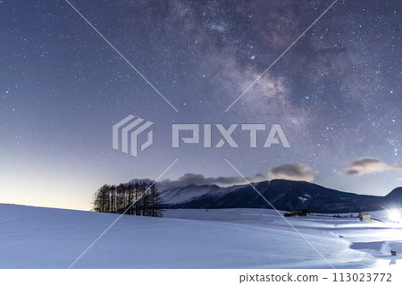 The Milky Way rises from the larch hills of Tsumagoi Kogen over a snowy field illuminated by moonlight 113023772