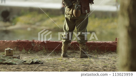 German Soldier Guards Mortar. Re-enactor Dressed As German Wehrmacht Infantry Soldier In World War Ii With Submachine Gun Mp 40 Patrols Territory Of Mortar Crew German Soldier Guards Mortar. Re-enactor Dressed As German Wehrmacht Infantry Soldier In World War Ii With Submachine Gun Mp 40 Patrols Territory Of Mortar Crew 113023959