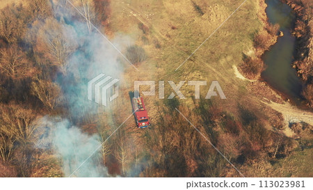 Aerial View. Spring Dry Grass Burns During Drought Hot Weather. Bush Fire And Smoke. Fire Engine, Fire Truck On Firefighting Operation. Wild Open Fire Destroys Grass. Ecological Problem Air Pollution 113023981