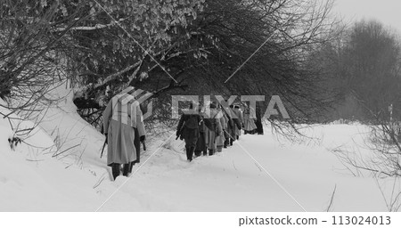 Men Dressed As White Guard Soldiers Of Imperial Russian Army In Russian Civil War s Marching Through Snowy Winter Forest. Army on Marching. Historical Reenactment of Civil War. Black And White 113024013