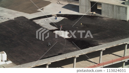 Man Workers Carries Out Work On Roof Waterproofing On Summer Sunny Day. Construction Works On Roof. Waterproofing Of Roof. Workers Cover Roof With Resin. View On Construction Work 113024031