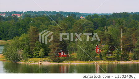 Panoramic View On Many Red Swedish Wooden Sauna Logs Cabins Houses On Island Coast In Summer Cloudy Day. Swedish Old Tradition Wooden Houses. Bold Colors. Travel to Sweden Panoramic View On Many Red Swedish Wooden Sauna Logs Cabins Houses On Island Coast In Summer Cloudy Day. Swedish Old Tradition Wooden Houses. Bold Colors. Travel to Sweden 113024063