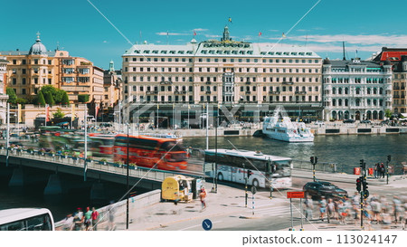 Stockholm, Sweden Traffic With Cars And Buses. Grand Hotel Located On The Peninsula Blasieholmen. Touristic Pleasure Boats Floating Near Famous Grand Hotel In Sunny Summer Day Stockholm, Sweden Traffic With Cars And Buses. Grand Hotel Located On The Peninsula Blasieholmen. Touristic Pleasure Boats Floating Near Famous Grand Hotel In Sunny Summer Day 113024147