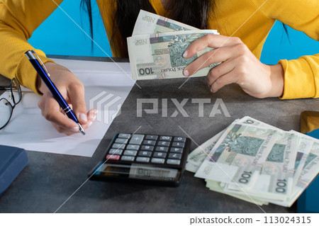 Female hands on the desk top while counting a large amount of banknotes. Female hands on the desk top while counting a large amount of banknotes. 113024315
