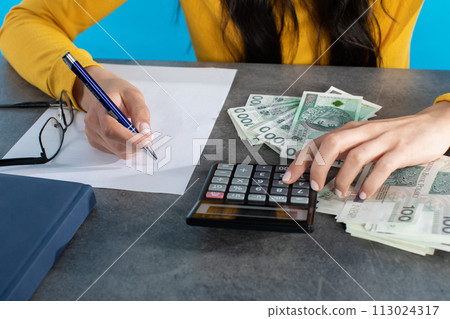 Female hands on the desk top while counting a large amount of banknotes. Female hands on the desk top while counting a large amount of banknotes. 113024317