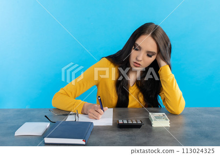 A rich young girl counts money at home at her desk for her next major financial investment. 113024325