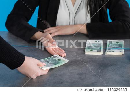 A bank teller accepts money from a client who transfers the cash to be paid into a bank account. A bank teller accepts money from a client who transfers the cash to be paid into a bank account. 113024335