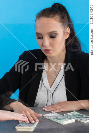 A bank teller accepts money from a client who transfers the cash to be paid into a bank account. A bank teller accepts money from a client who transfers the cash to be paid into a bank account. 113024343
